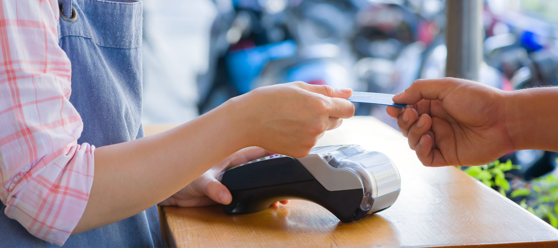 customer handing credit card to teller with credit card machine