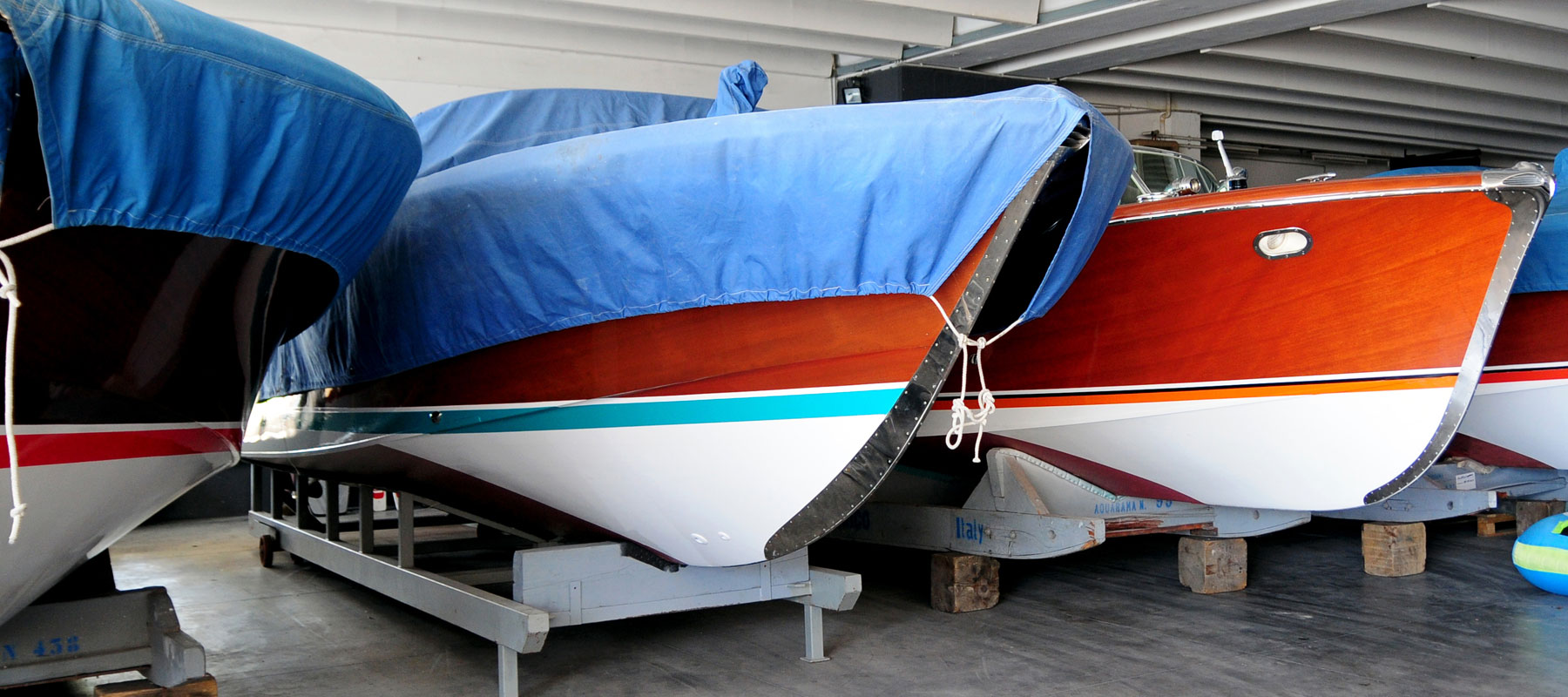 three boats lined up inside with blue covers